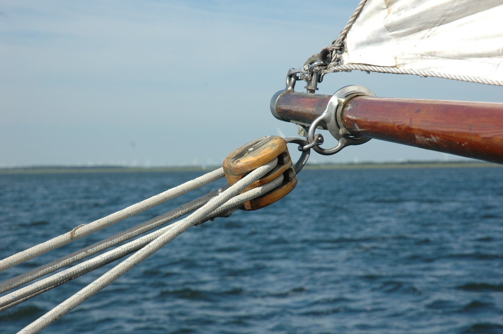 Zeil, giek en touwen met een houten katrol boven het water
